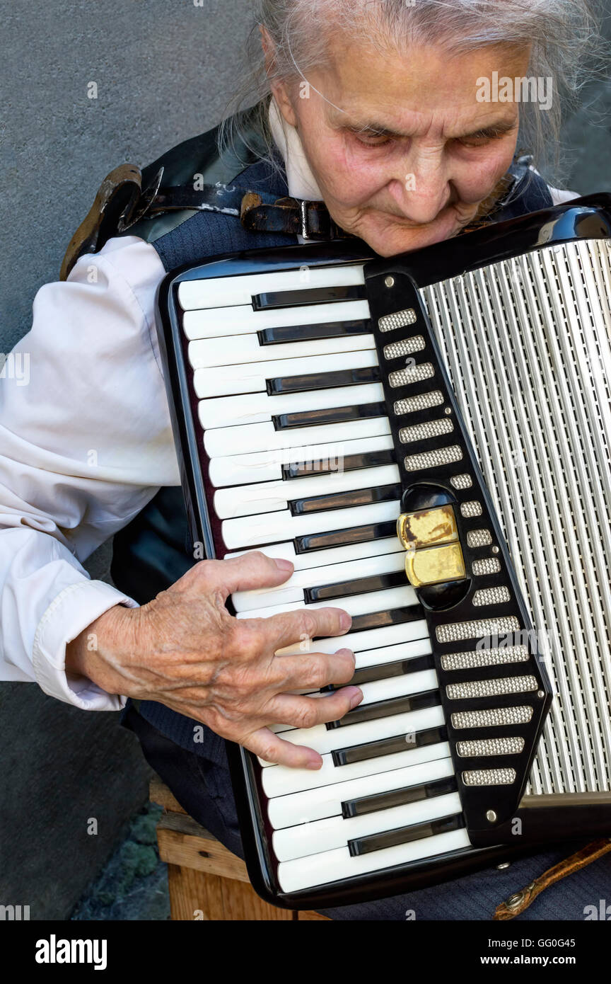 Elderly woman playing old accordion. Stock Photo