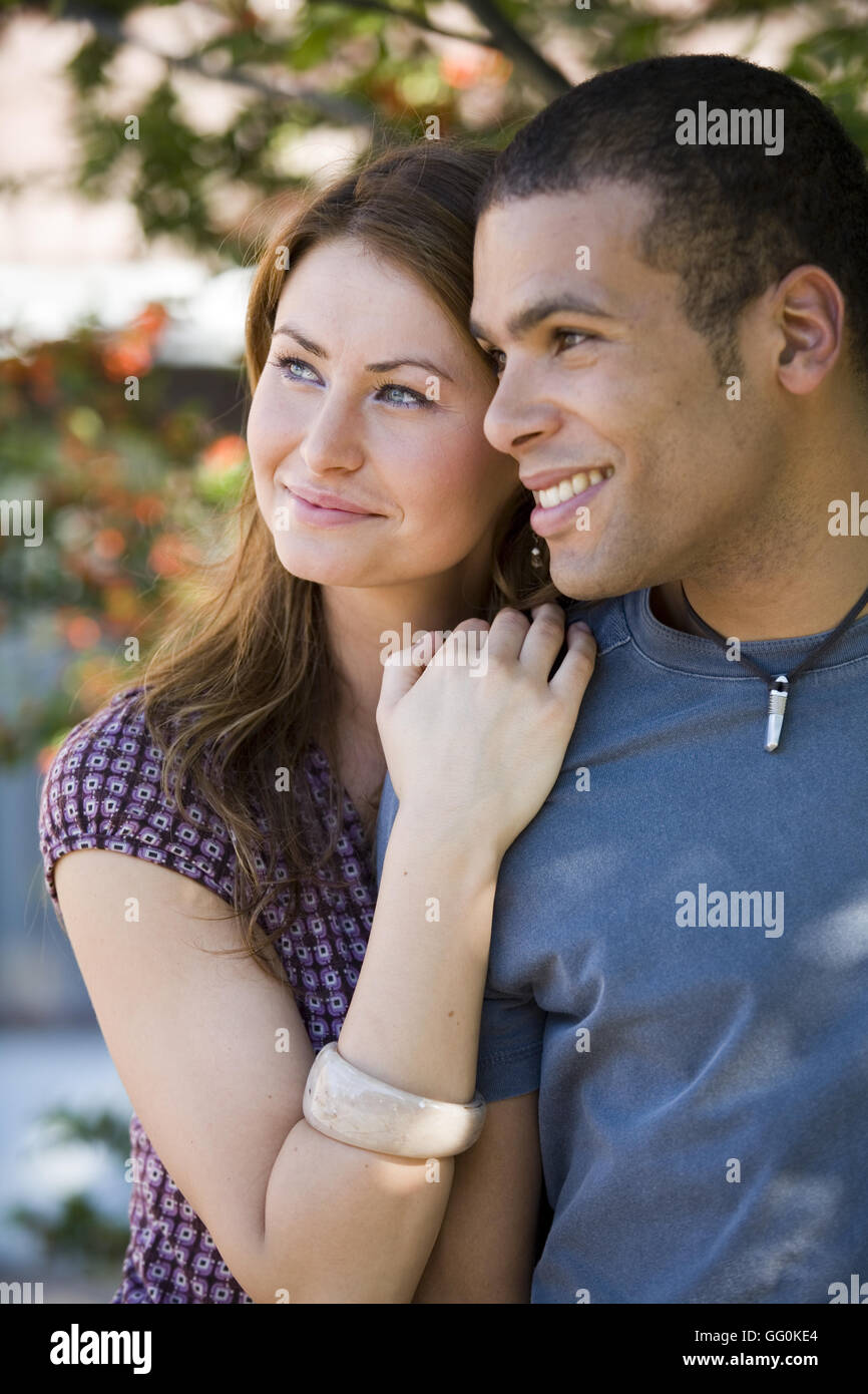 beautiful happy young multi ethnic couple outside holding each other close. Stock Photo