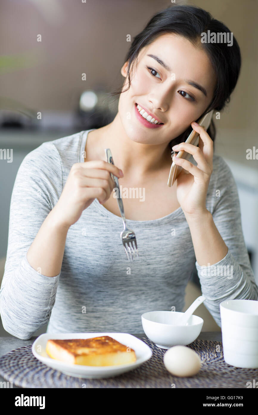 Young Chinese woman eating breakfast at home Stock Photo