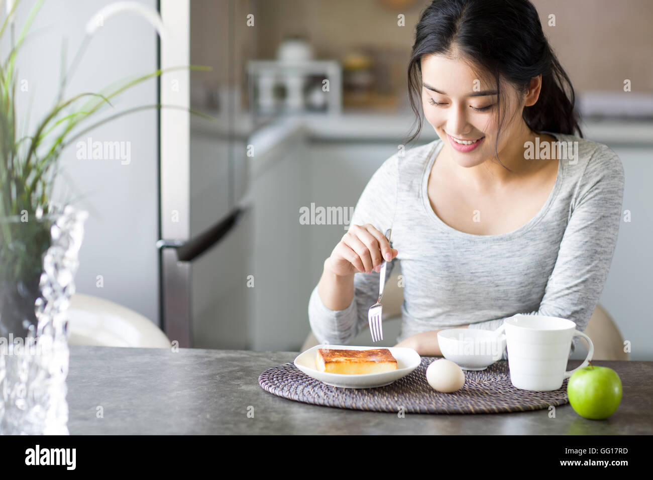 Young Chinese woman eating breakfast at home Stock Photo
