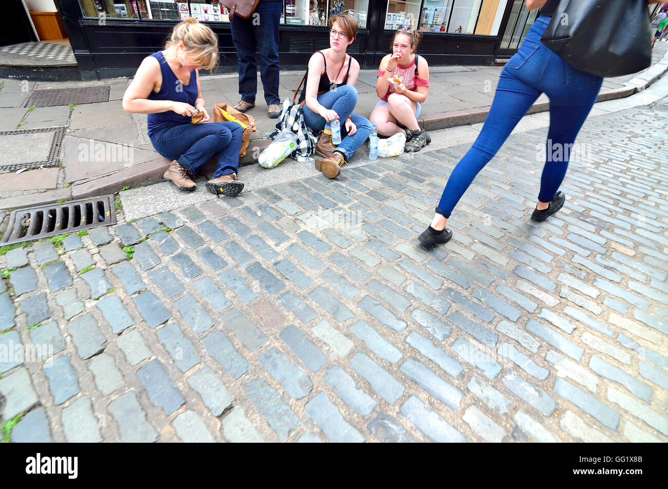 Canterbury, Kent, UK. Girls eating sitting on the pavement. Stock Photo