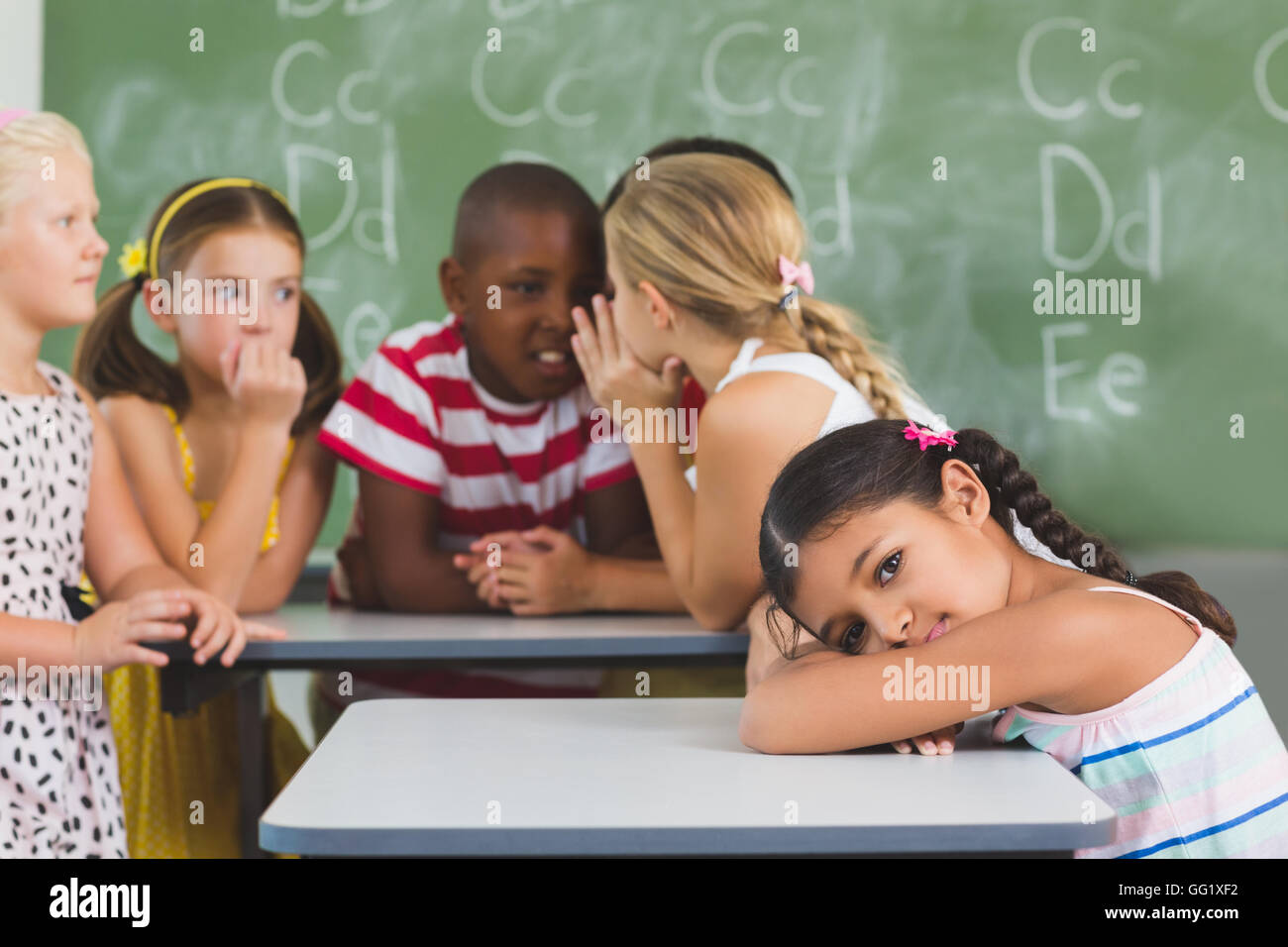 Portrait of schoolgirl lying on desk in classroom Stock Photo - Alamy