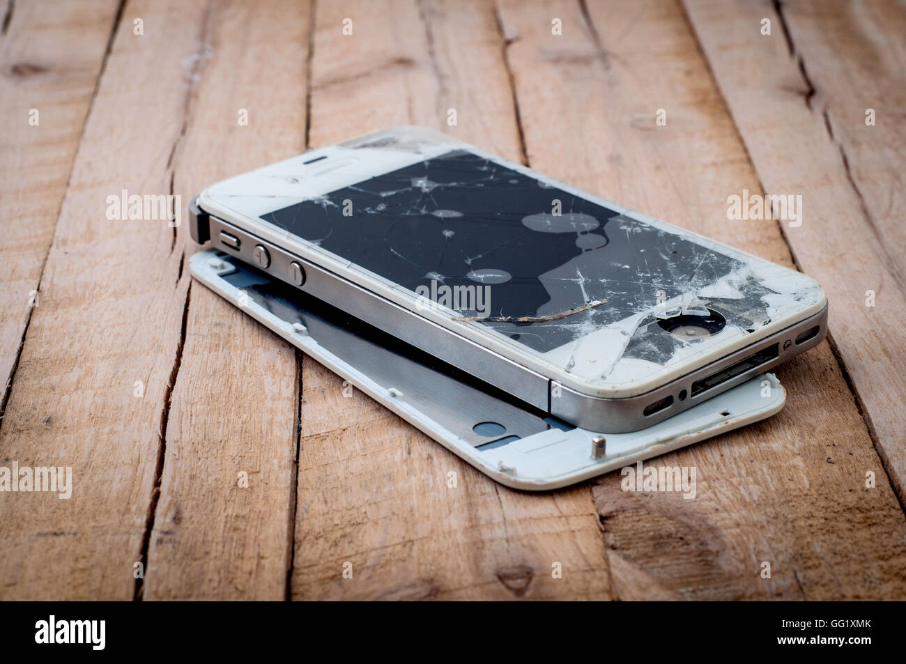 Broken iPhone 4s on wooden table Stock Photo