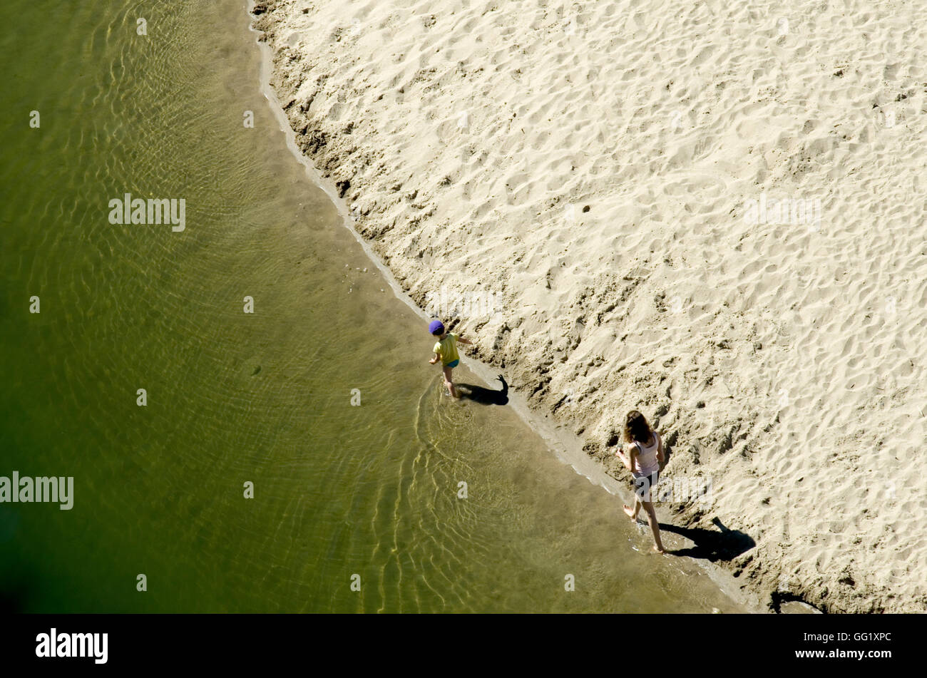 Mother and son walking along the shoreline of a river beach in the Ardeche region of France. Taken from above. Stock Photo