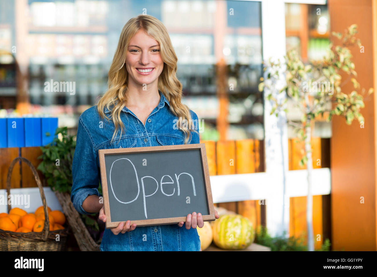 Smiling female staff holding open sign board in super market Stock Photo
