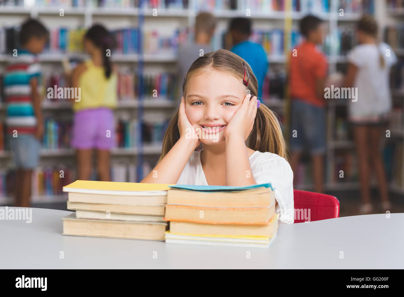 Portrait of girl sitting with pile of books in library Stock Photo - Alamy