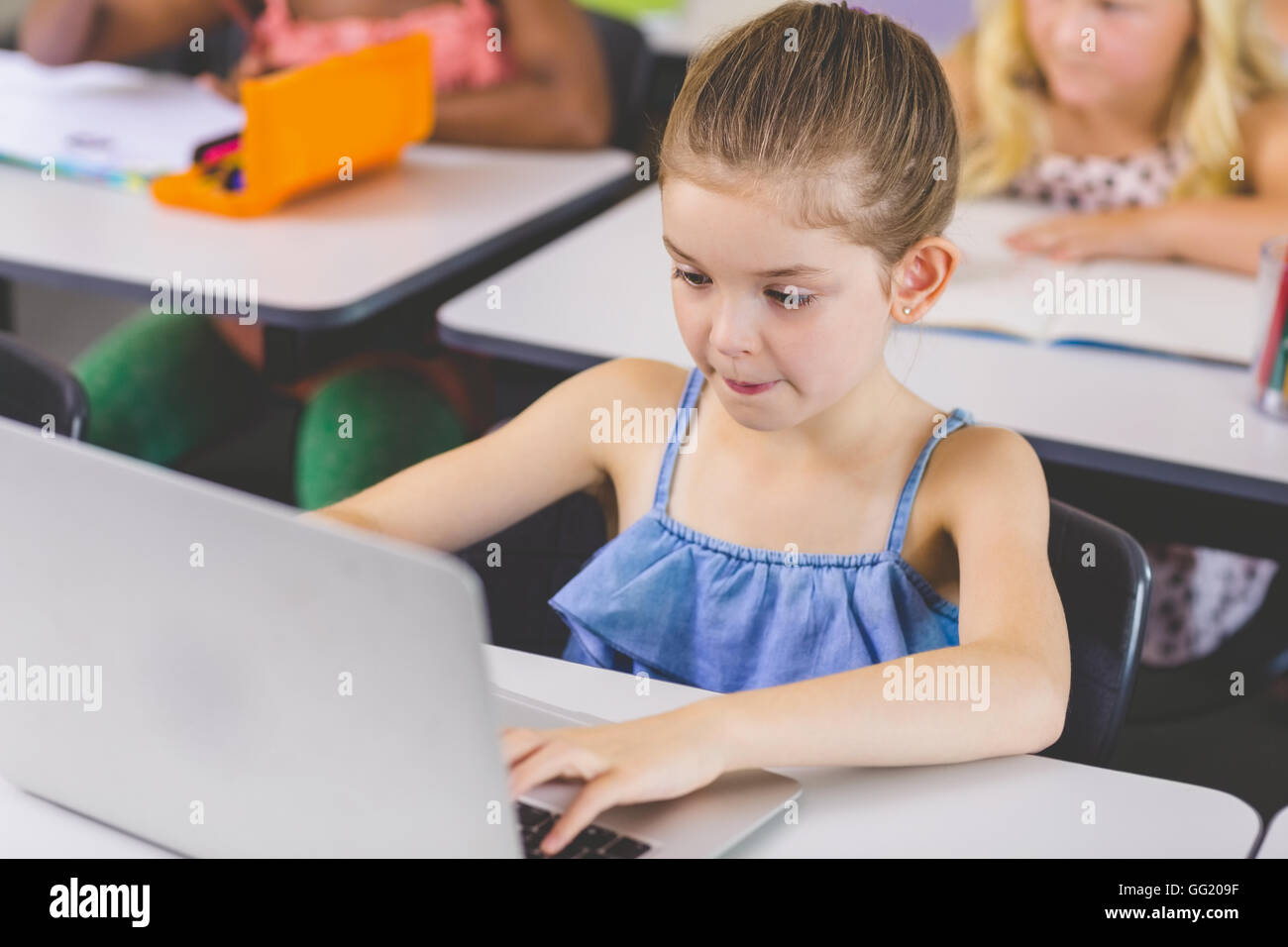 Schoolgirl using laptop in classroom Stock Photo - Alamy