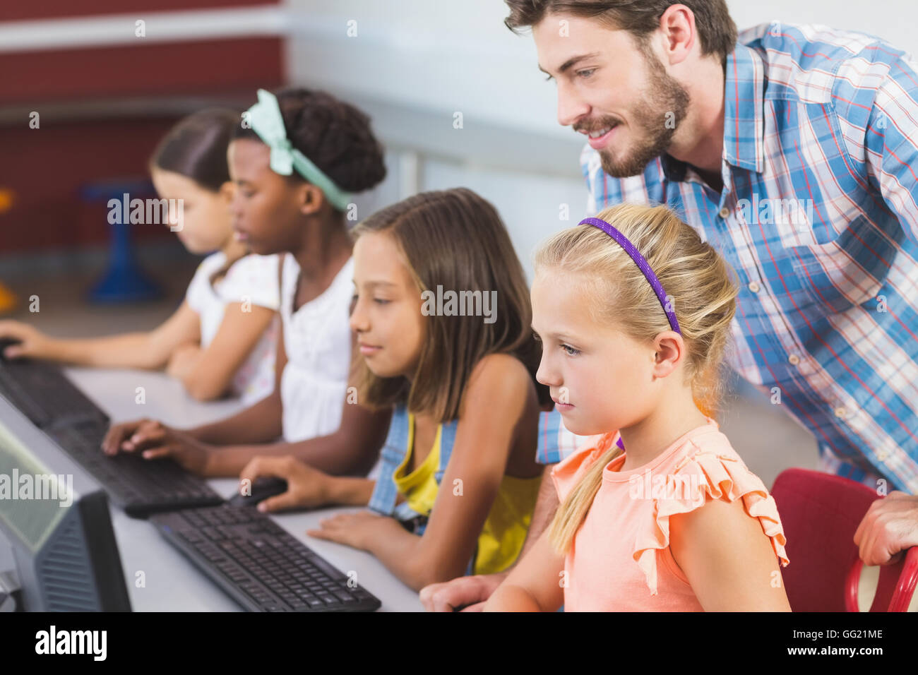 Teacher assisting schoolgirls in learning computer Stock Photo - Alamy