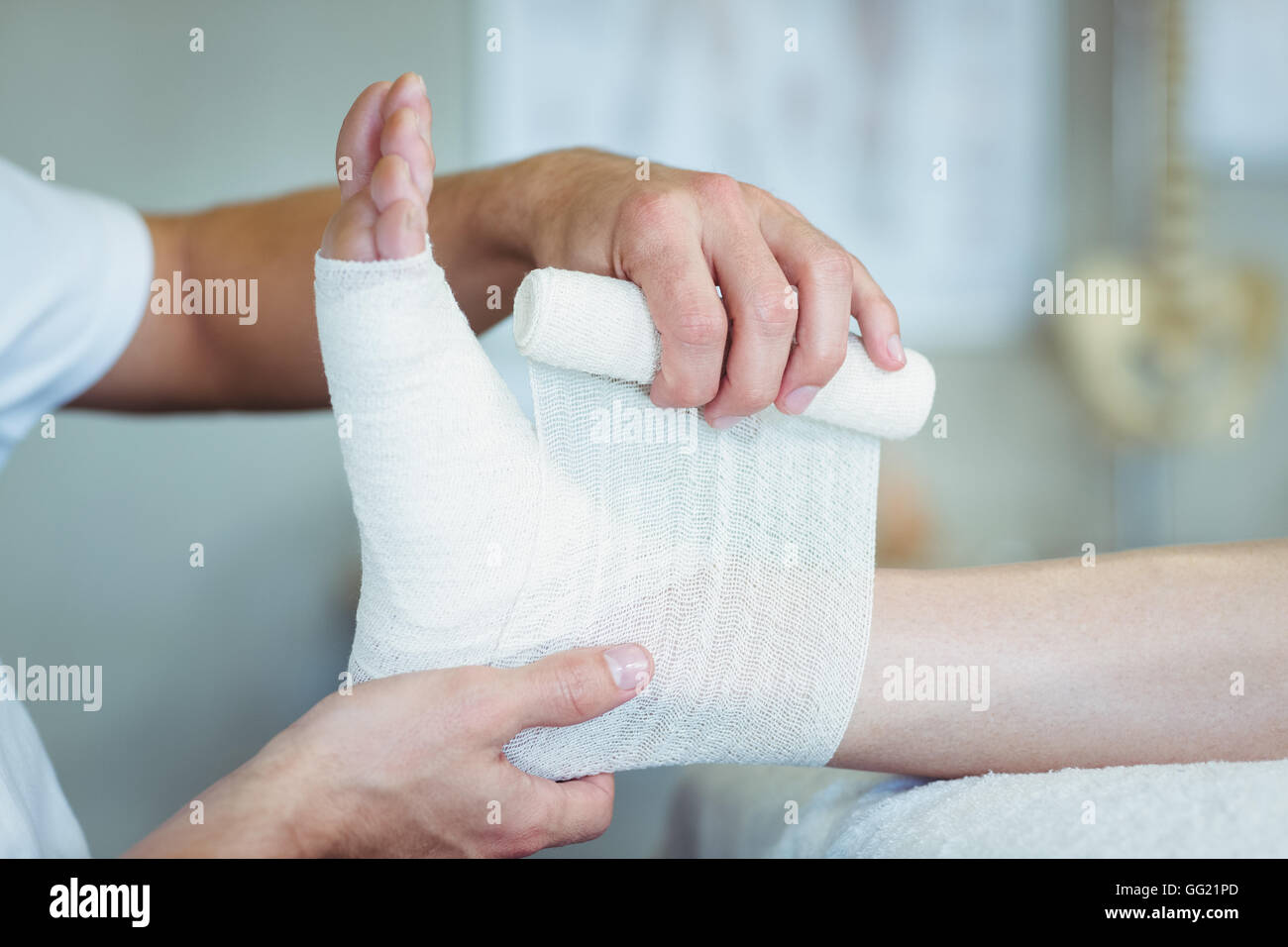 Physiotherapist putting bandage on injured feet of patient Stock Photo