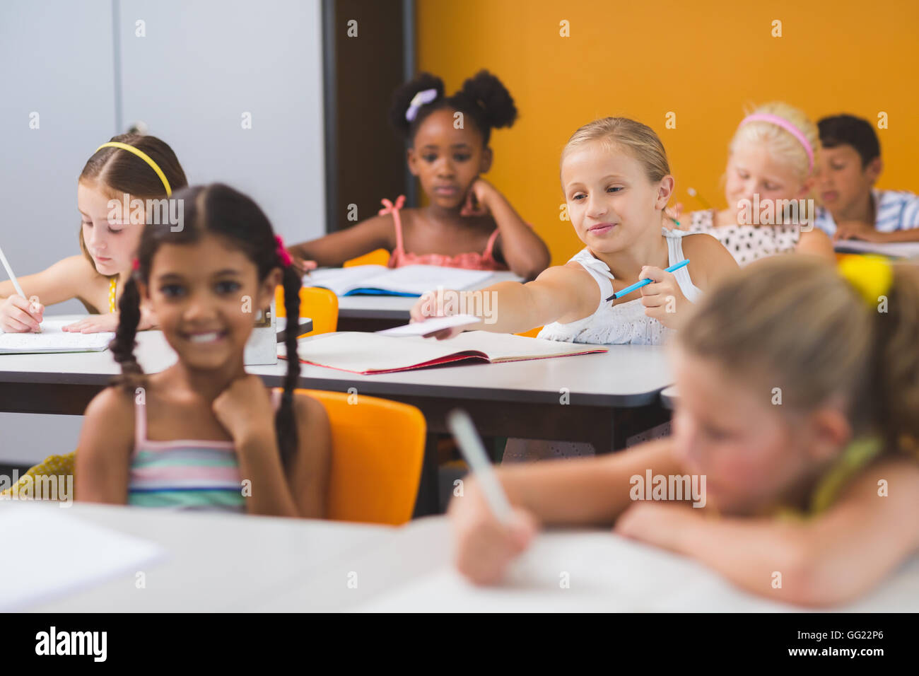 Schoolgirl giving chit to her friends in classroom Stock Photo
