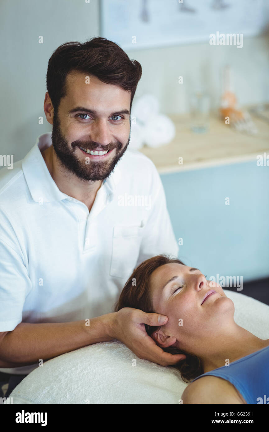 Smiling physiotherapist giving head massage to a woman Stock Photo