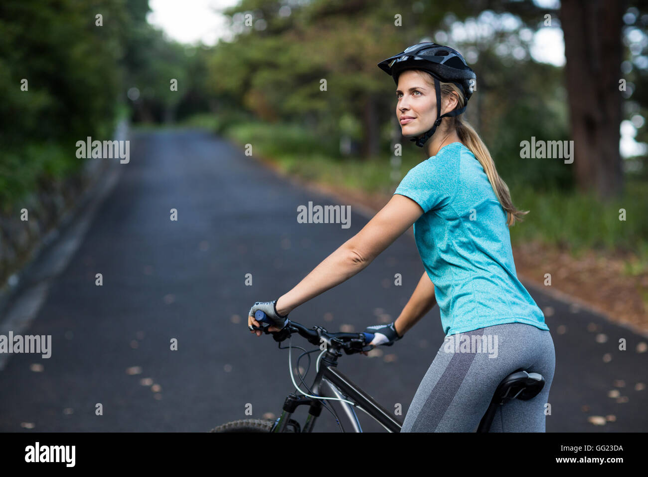 Woman standing with mountain bike on the open road Stock Photo