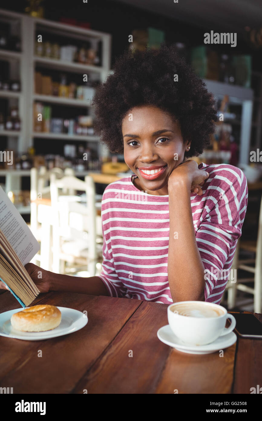 Smiling woman reading a book in cafe Stock Photo - Alamy