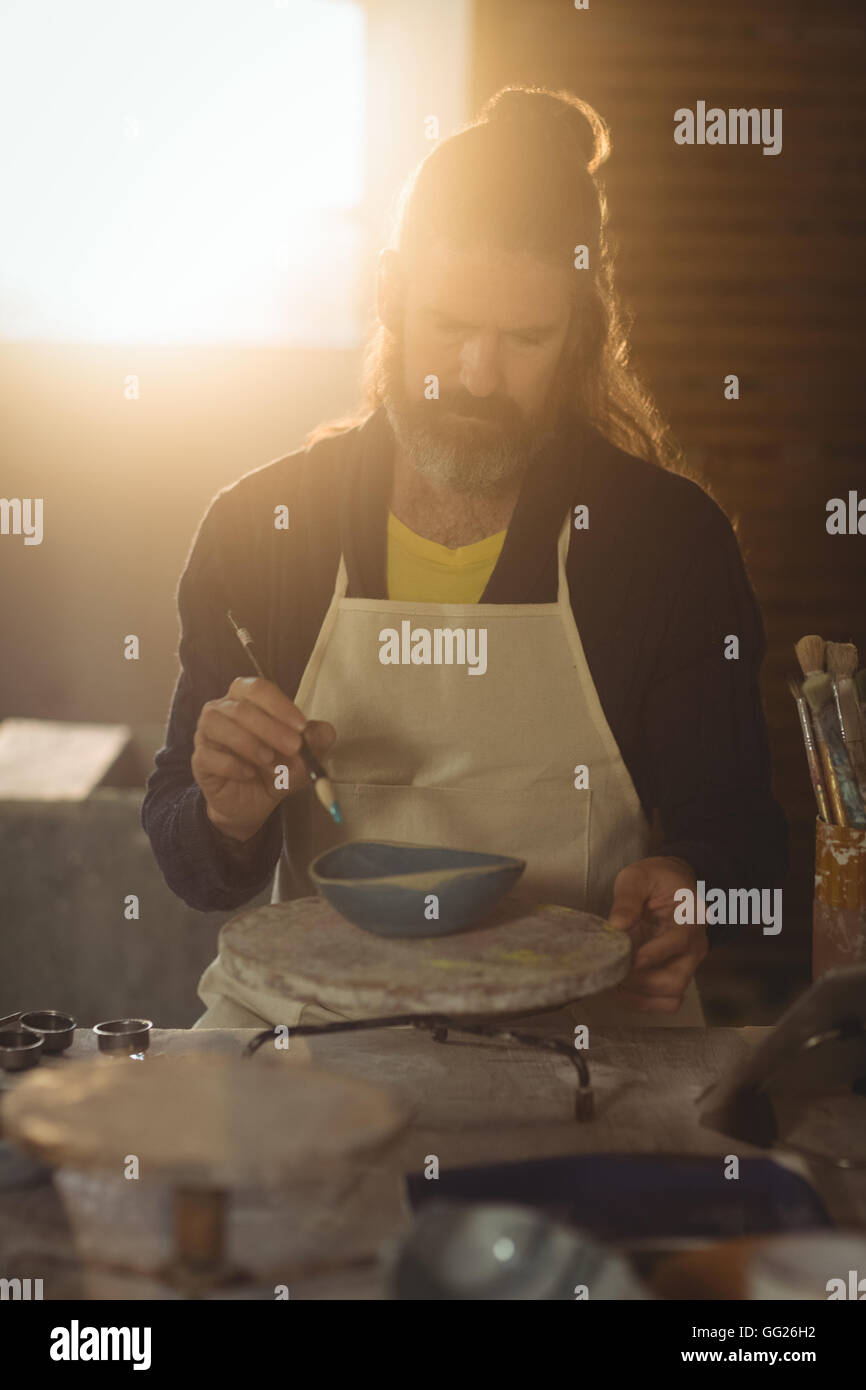 Attentive male potter painting on bowl Stock Photo - Alamy
