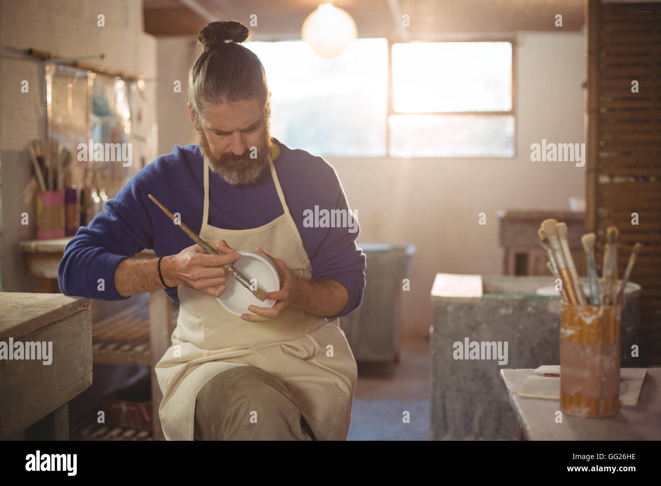 Male potter painting on bowl Stock Photo - Alamy