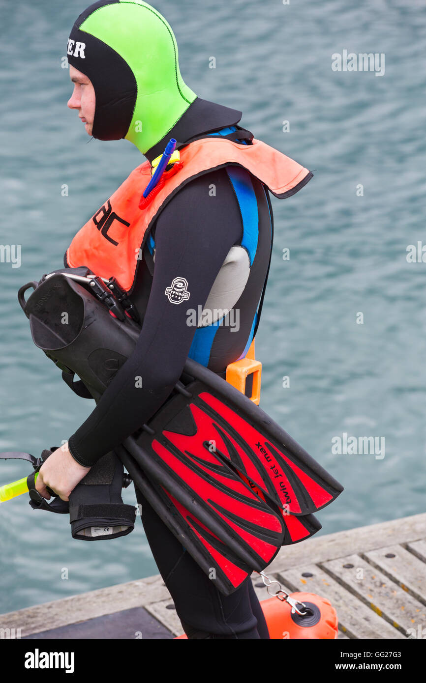 Scuba diver in fluorescent coloured gear waiting to go in sea at Swanage in July Stock Photo