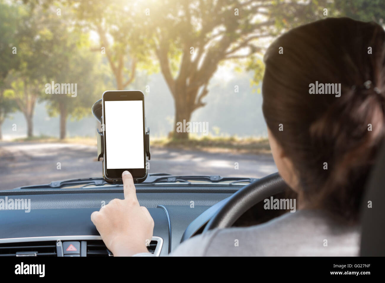 woman use phone mount to glass in car on rural road Stock Photo