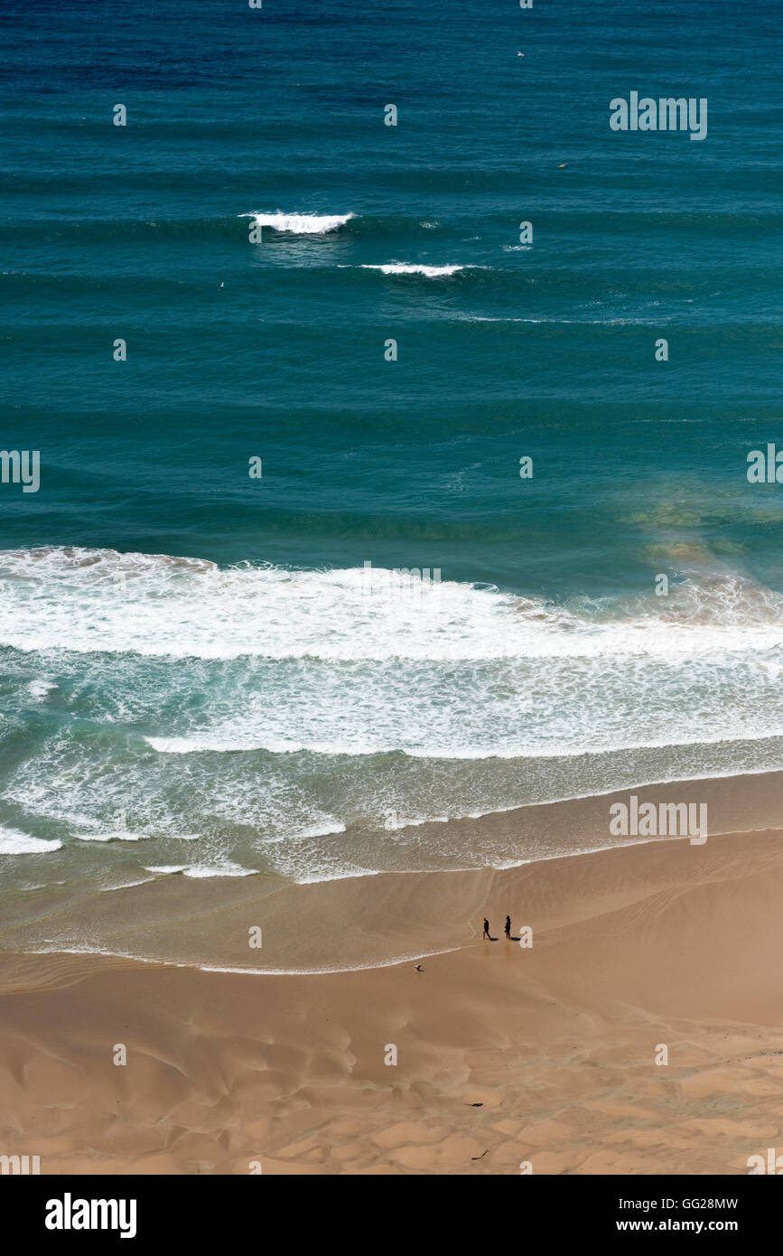 Two people in the distance walking on the beach at Bedruthan Cornwall UK in a wide open space outdoors Stock Photo