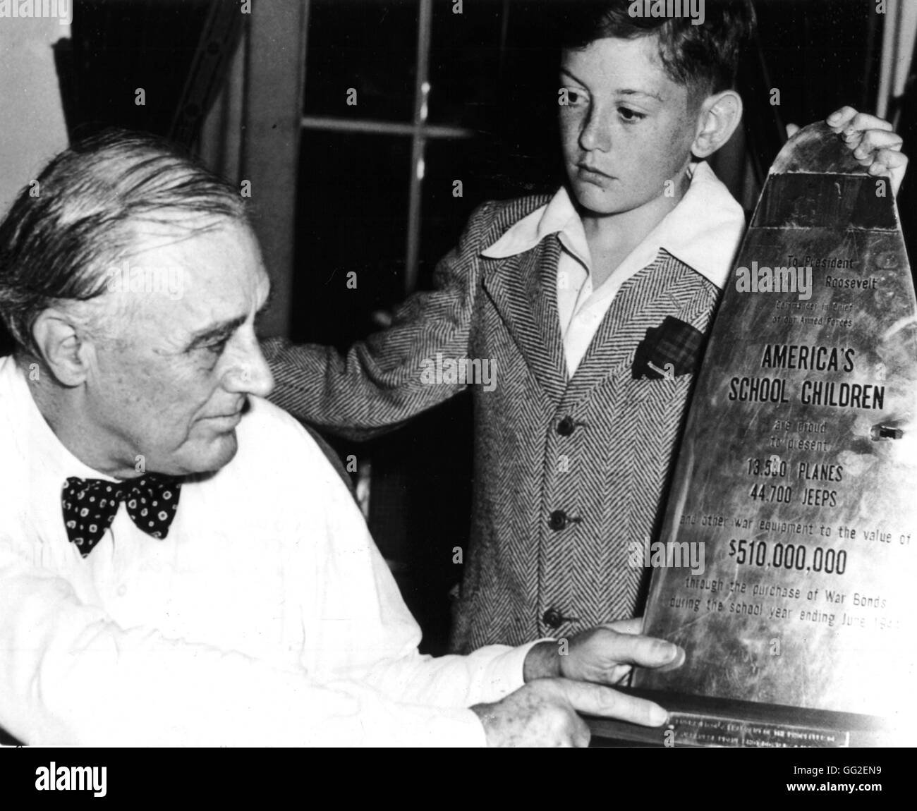President Roosevelt examining a piece of propeller of a Japanese plane shot down, on which is written the financial participation of school children during the war. The school children's delegate is Donald Buck, aged 13. 1944 United States - World War II Stock Photo