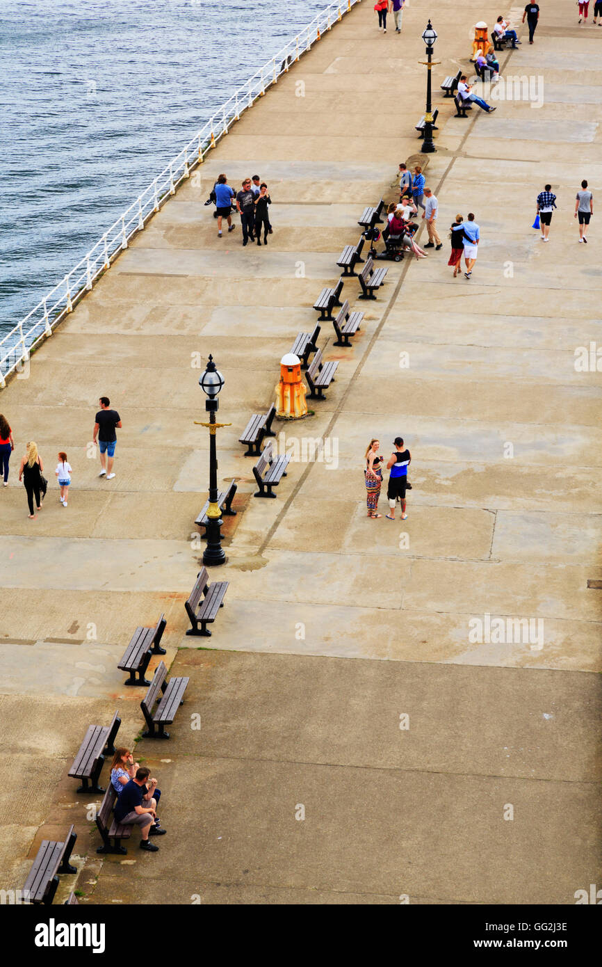 People walking along the breakwater, Whitby,seen from the top of the light tower. North Yorkshire, England Stock Photo