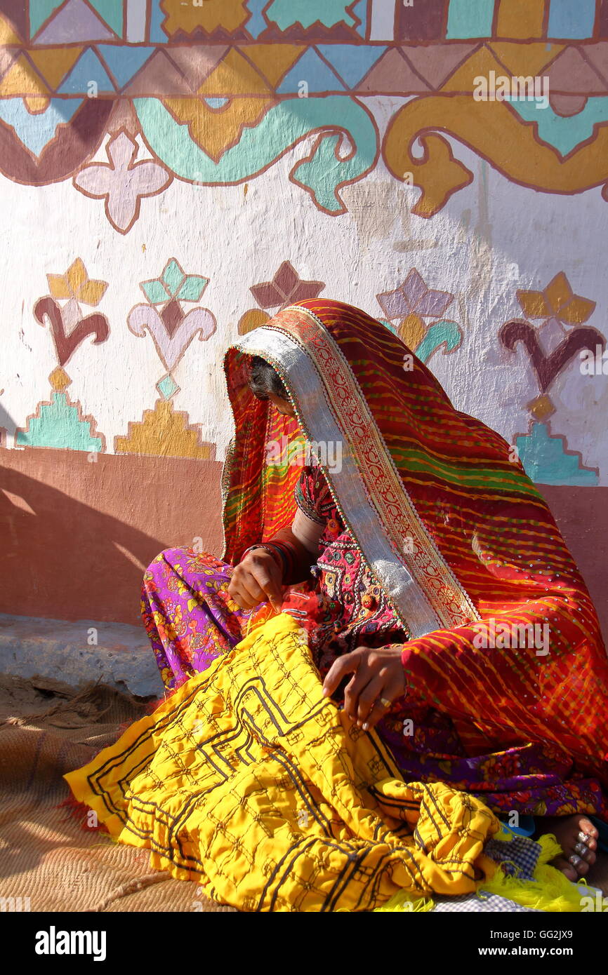 Tribal woman practising embroidery in front of her house (Bhunga) in a local village near Bhuj, Gujarat, India Stock Photo