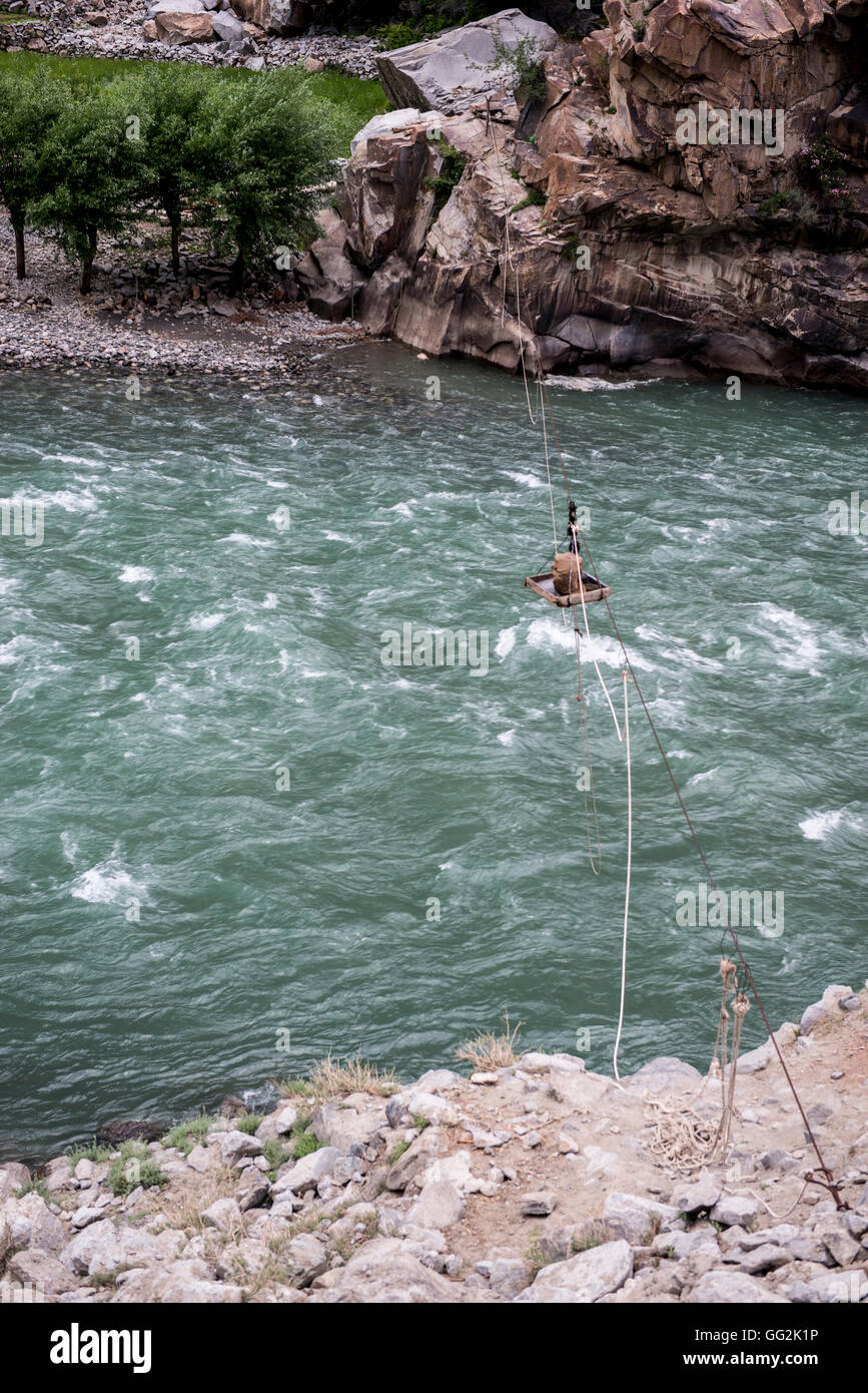 Man using a tray bridge over the Gilgit river (also known as the Ghizar River.) Stock Photo