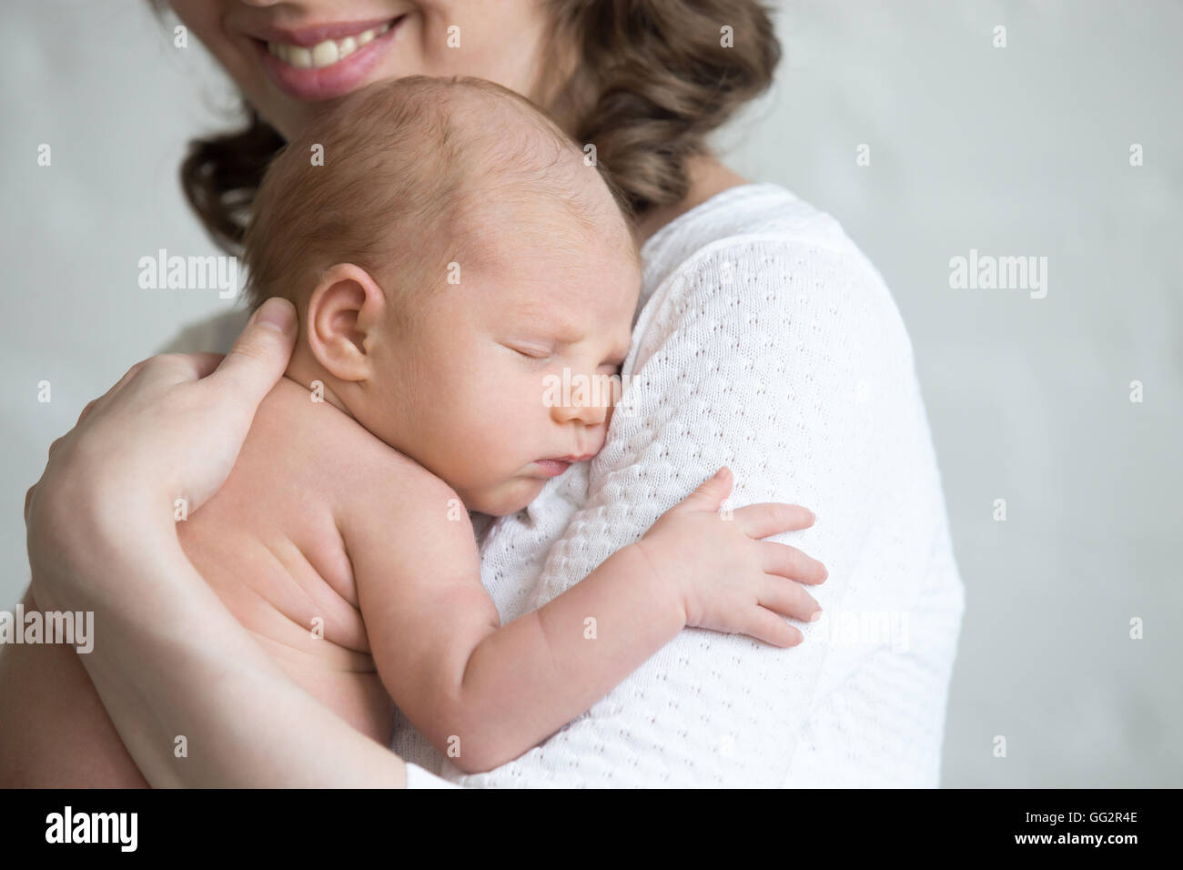 Newborn babe napping on woman arms. Young happy mother tenderly hugging