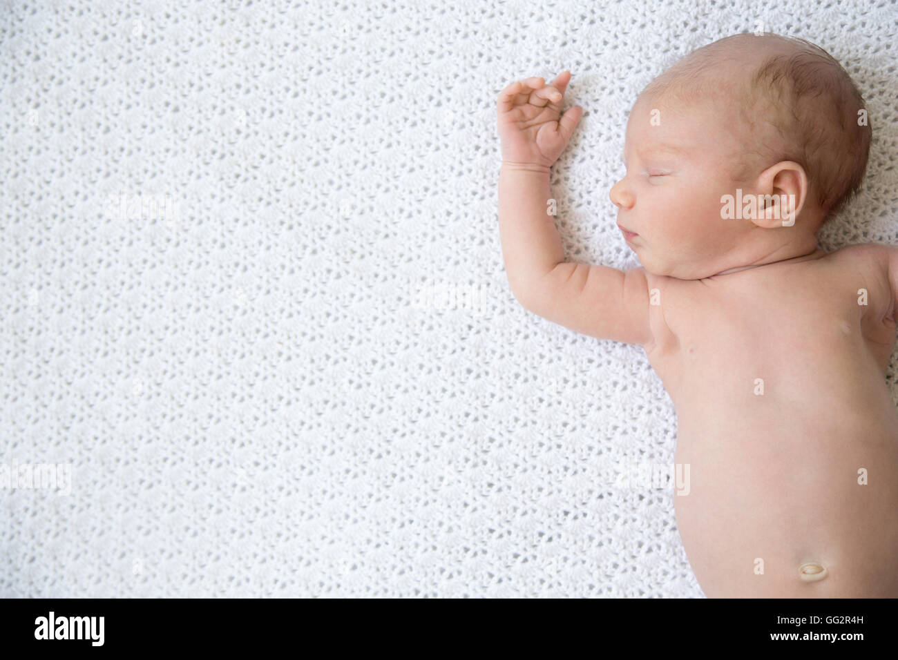 Closeup portrait of young funny newborn babe napping on white knitted blanket. Sleeping adorable new born child. Healthy little Stock Photo