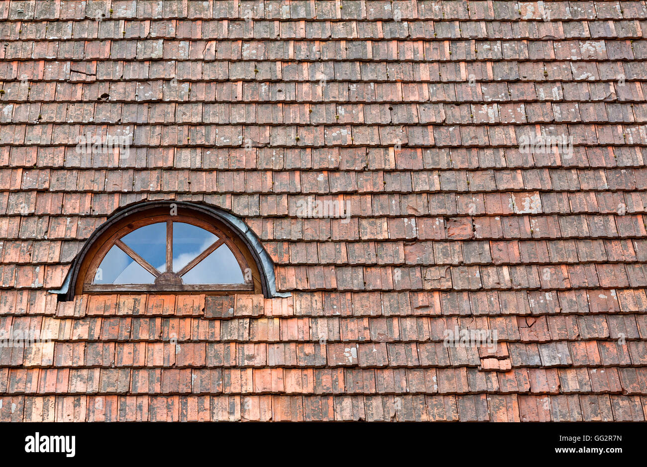 Old red weathered roof tiles with dormer window Stock Photo
