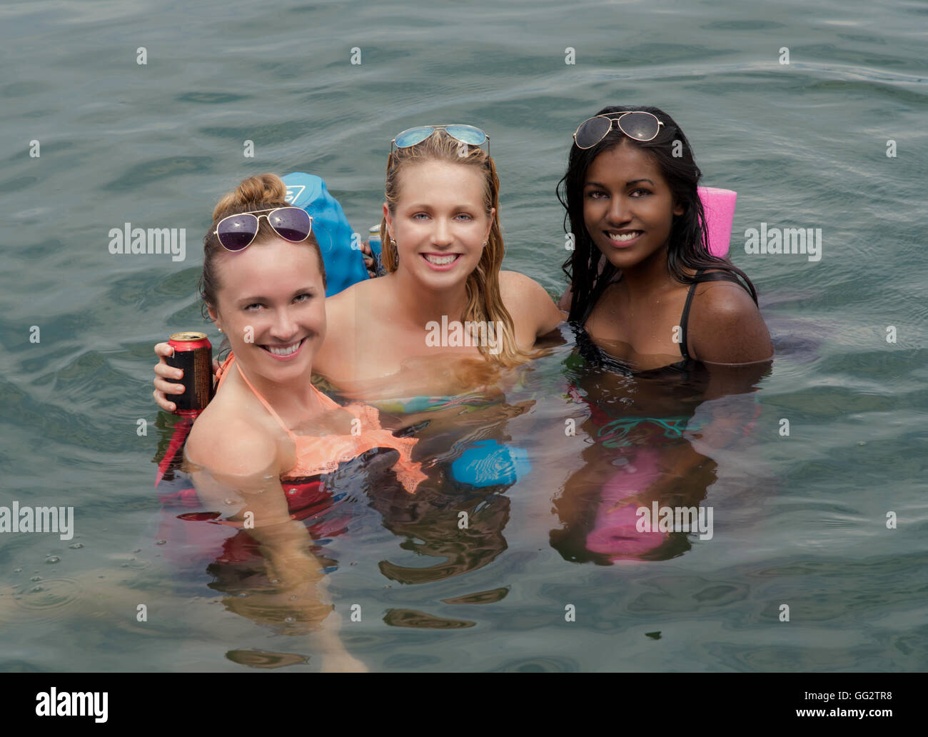 A portrait of three 20's women enjoy a summer float in a lake. Stock Photo