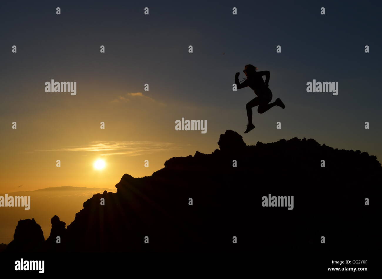 young sporty woman girl jumps in the air on a mountain at sunset sunrise Stock Photo