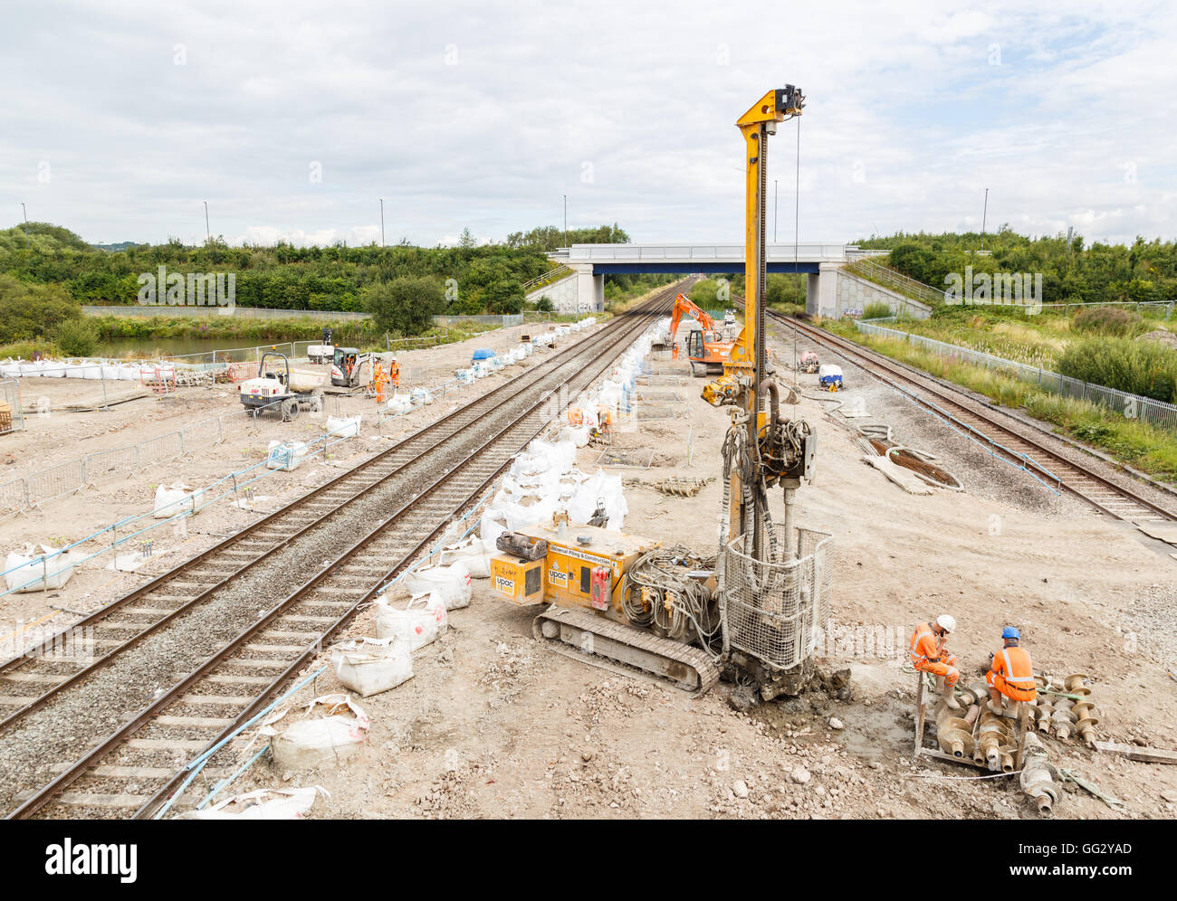Construction workers, and pile drilling machine, on site next to a section of railway track. In Ilkeston, Derbyshire, England. Stock Photo
