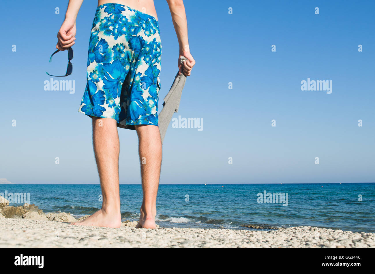 Surfer standing near the ocean on the beach against the backdrop of beautiful landscape Stock Photo