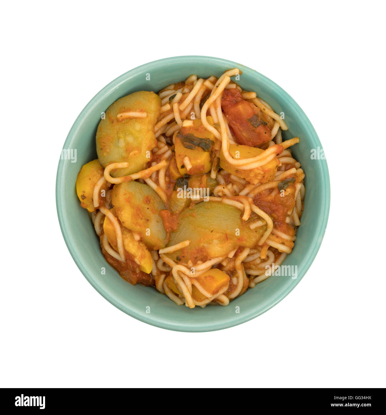 Top view of a TV dinner of angel hair pasta with zucchini and spinach in a small green bowl on a white background. Stock Photo