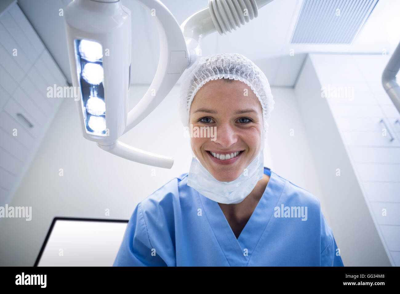 Dental assistant smiling at camera beside light Stock Photo