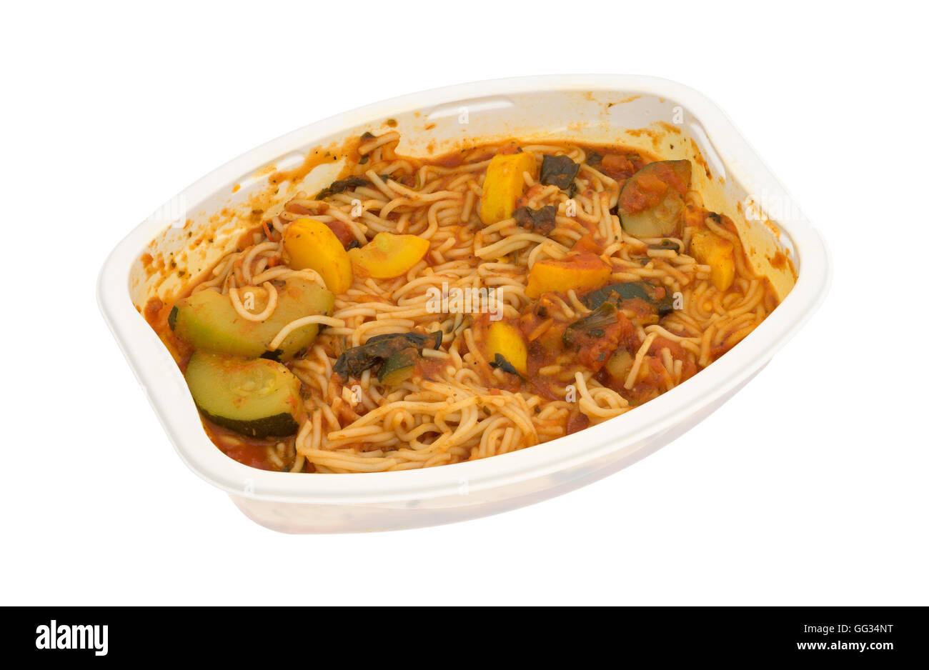 A cooked TV dinner of angel hair pasta with zucchini and spinach in a microwaveable tray on a white background. Stock Photo