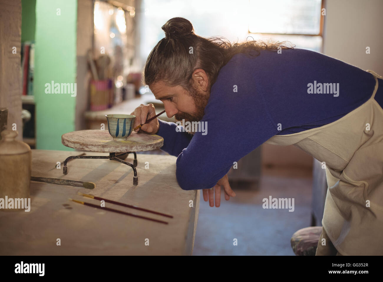 Attentive male potter painting on bowl Stock Photo - Alamy