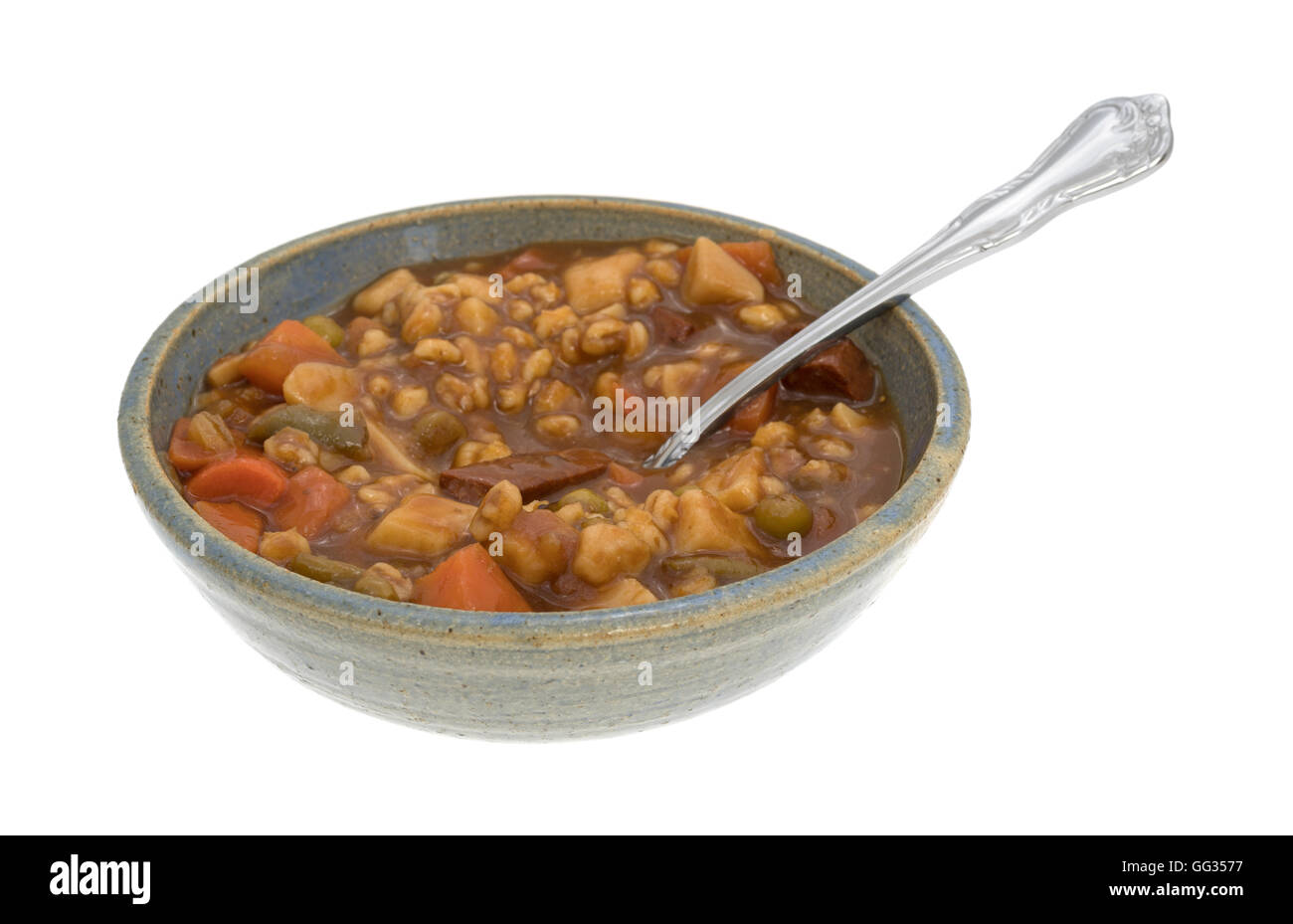 A serving of canned beef stew in an old bowl with a spoon inserted into
