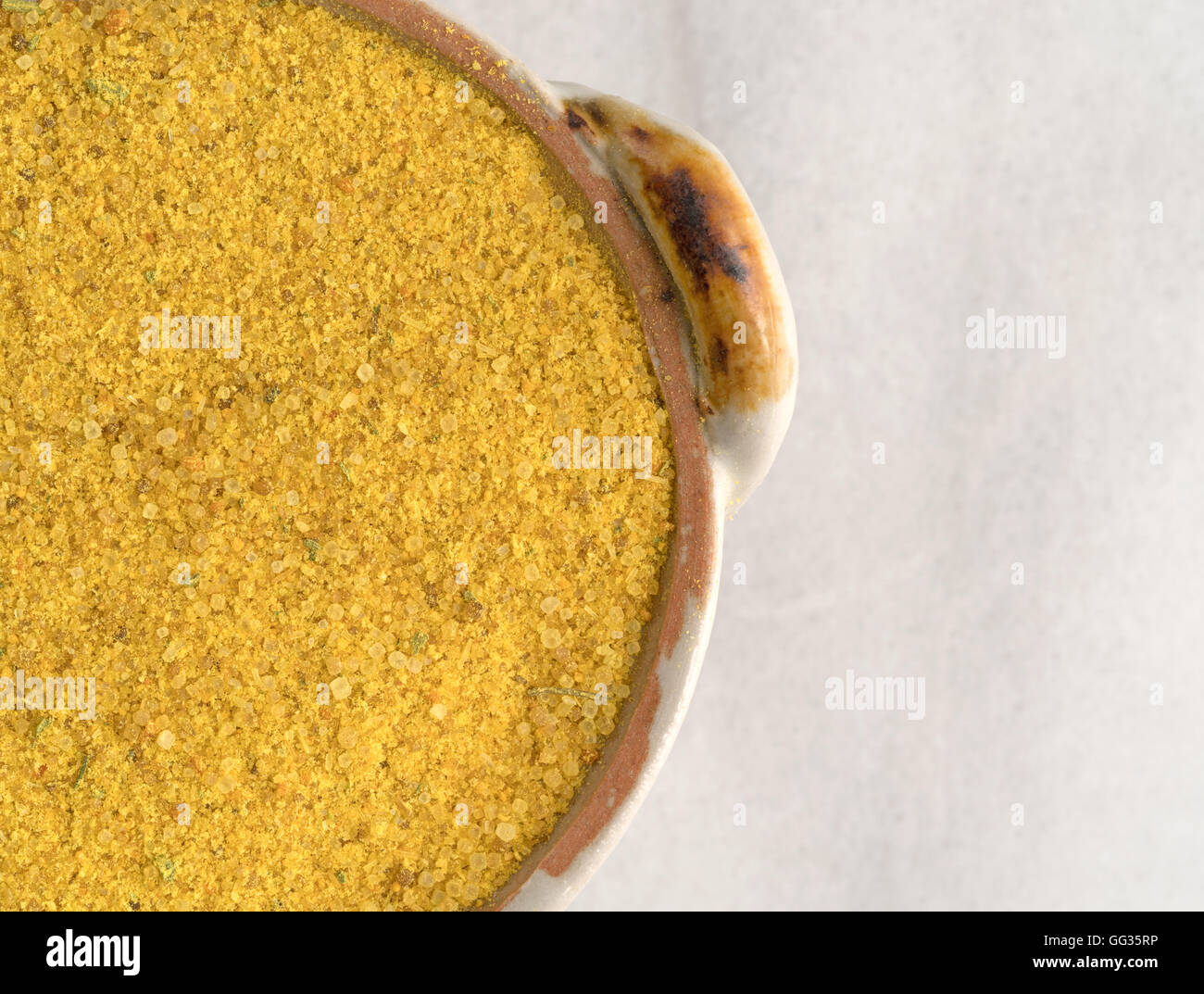 Top close view of a portion of chicken flavored bouillon in a small dish on a marble cutting board. Stock Photo