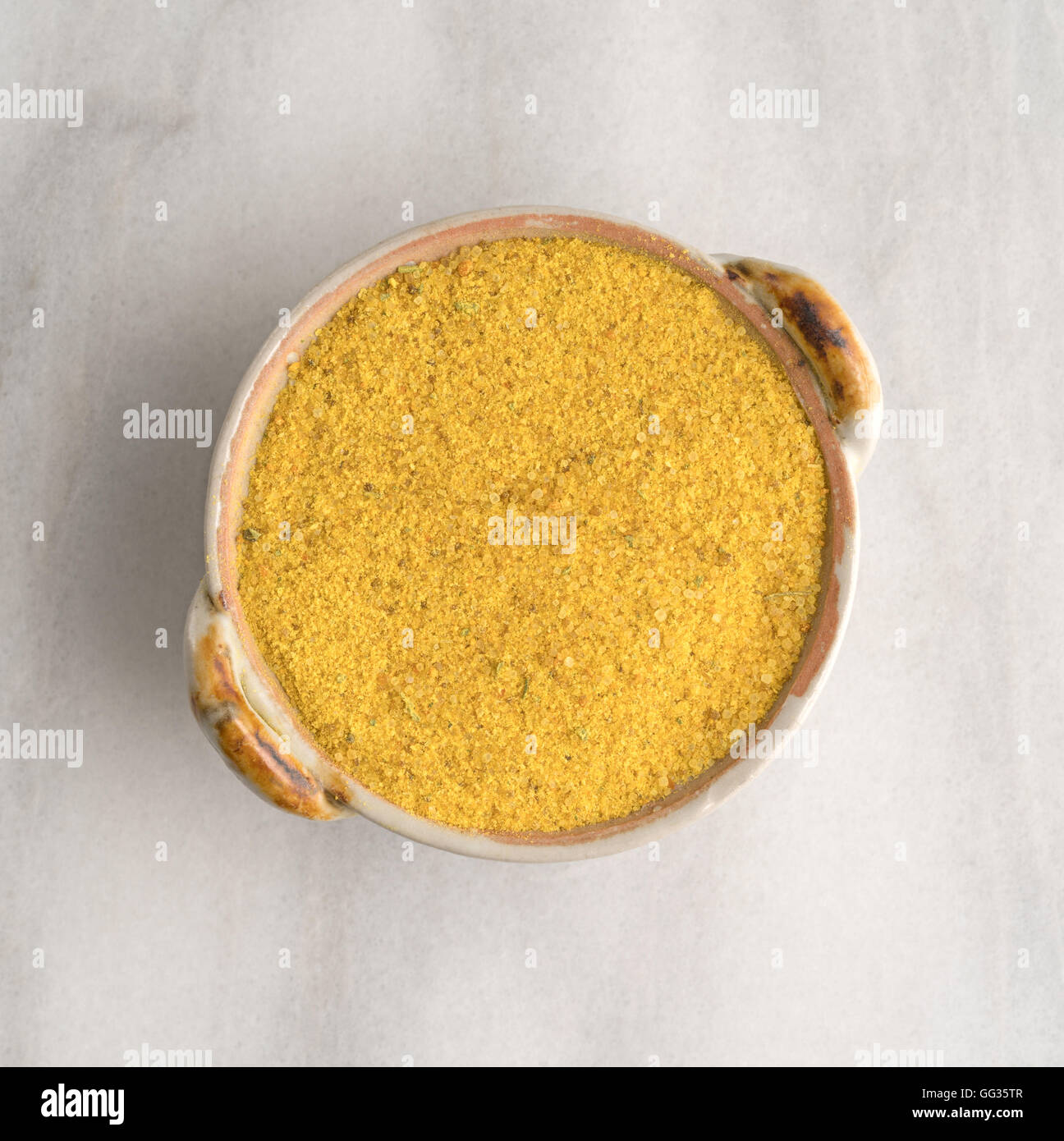 Top view of a portion of chicken flavored bouillon in a small dish on a marble cutting board. Stock Photo