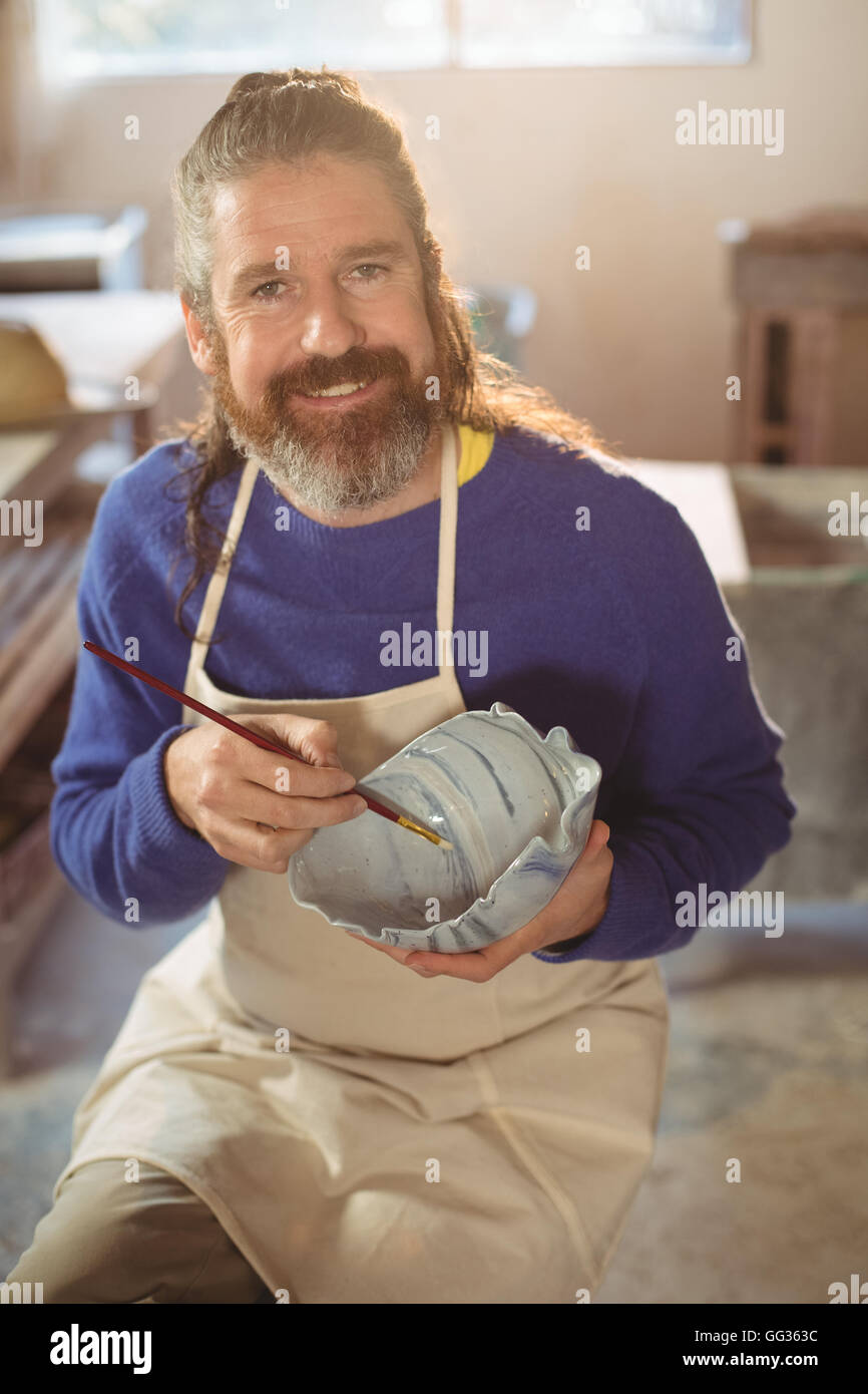 Smiling male potter painting on bowl Stock Photo - Alamy