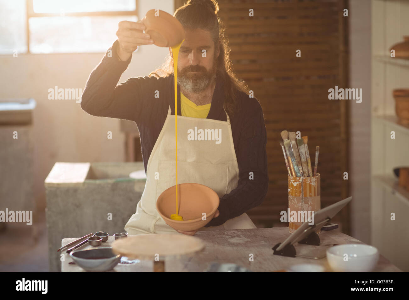 Male potter pouring watercolor in bowl Stock Photo - Alamy
