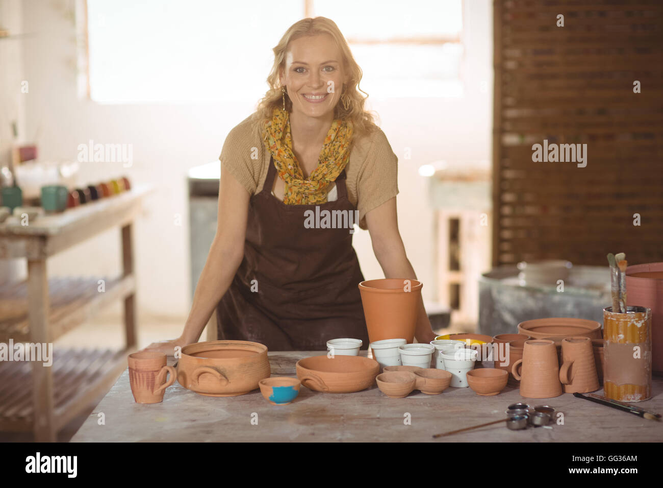 Beautiful female potter leaning on worktop Stock Photo