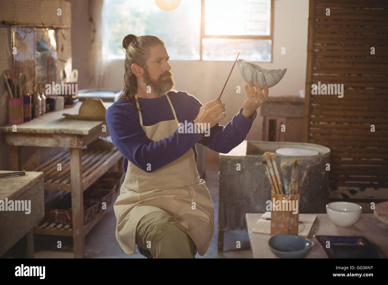 Attentive male potter painting on bowl Stock Photo - Alamy