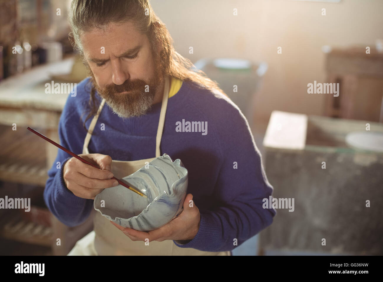 Attentive male potter painting on bowl Stock Photo - Alamy