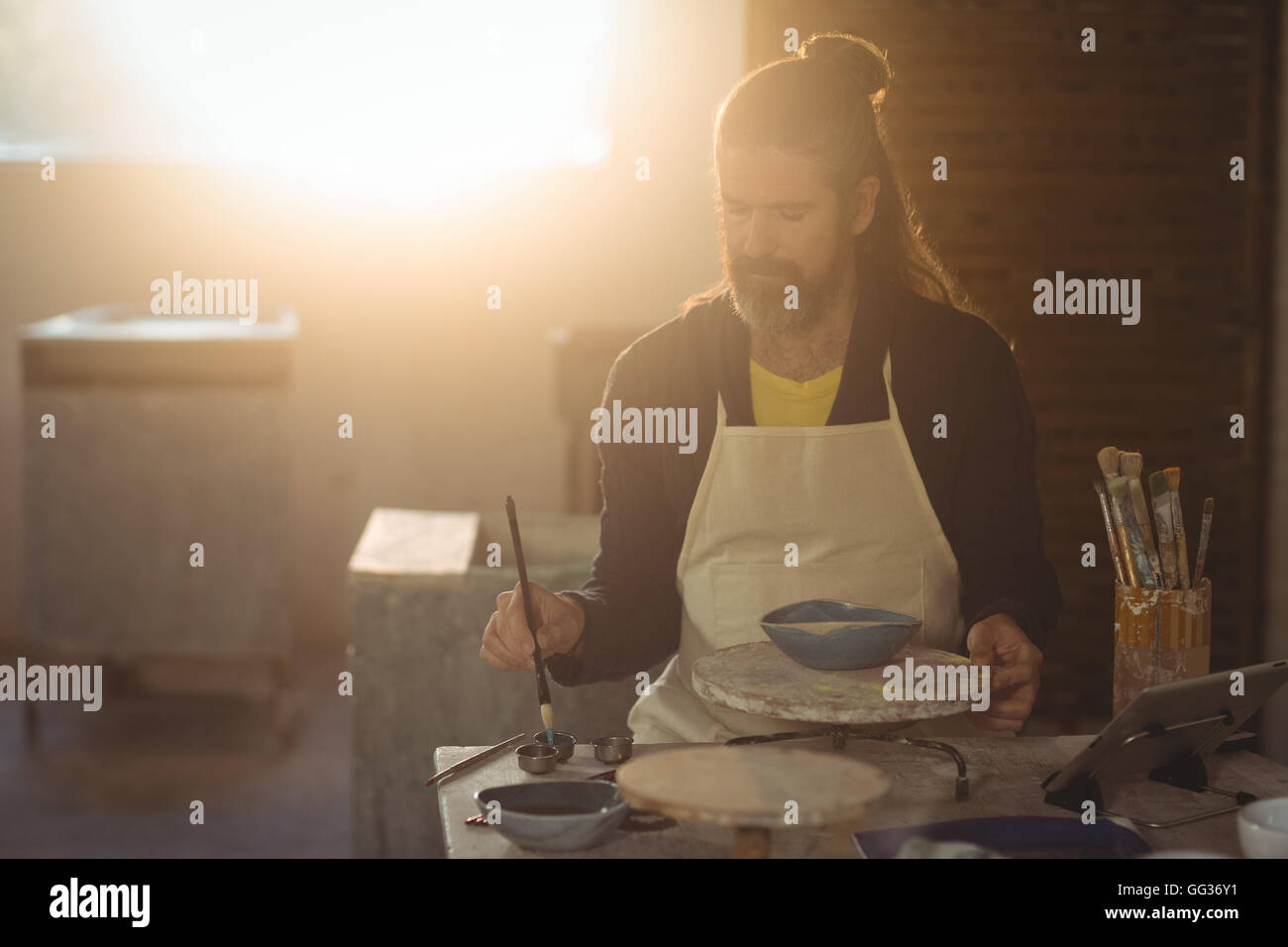 Attentive male potter painting on bowl Stock Photo - Alamy