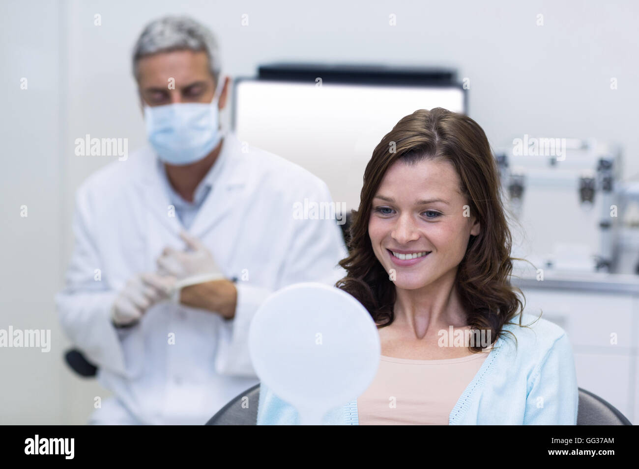 Patient checking her teeth in mirror Stock Photo