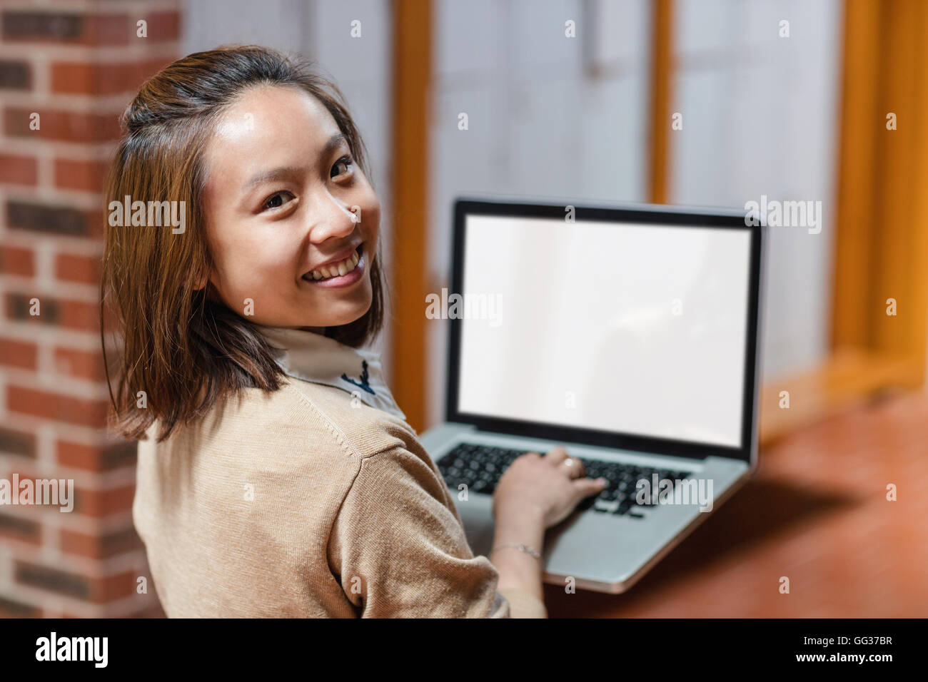 Young woman using laptop in corridor Stock Photo - Alamy