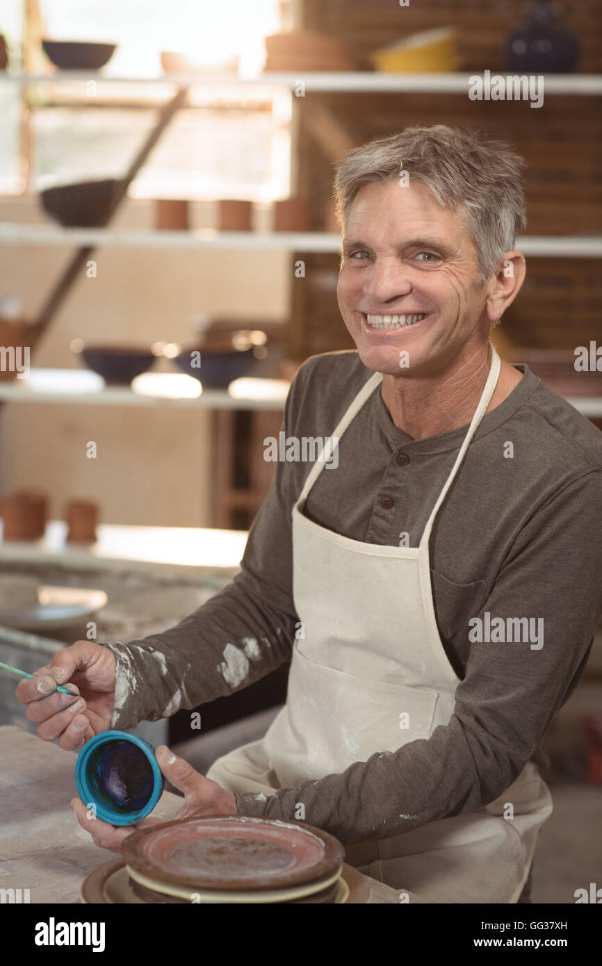 Smiling male potter painting on bowl Stock Photo - Alamy
