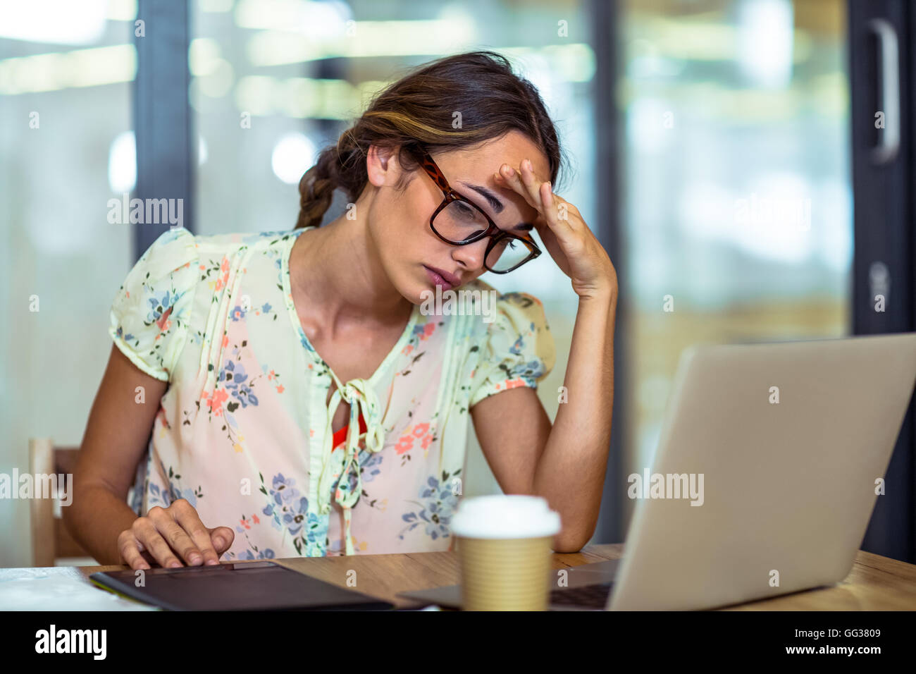 Frustrated female graphic designer looking at laptop Stock Photo